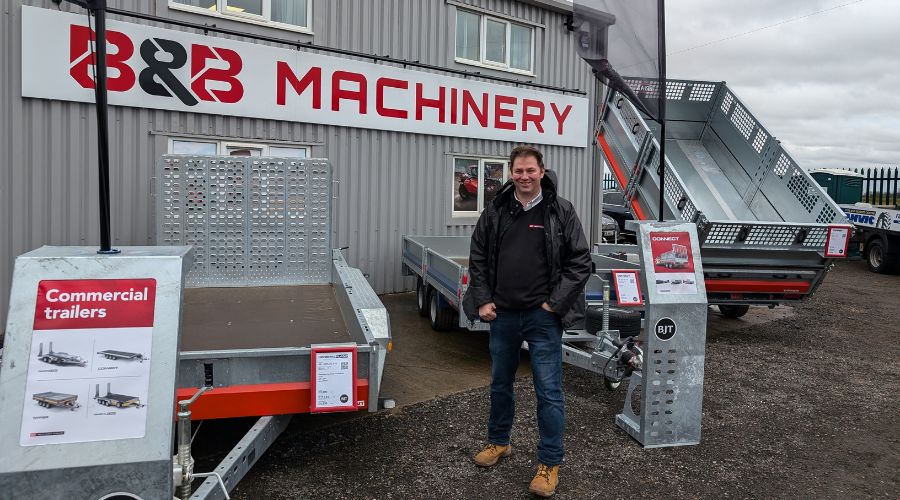 BJT’s business development manager Jim Cherry standing with two trailers in front of B&B Machinery depot